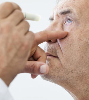 Optometrist checking older man's eye