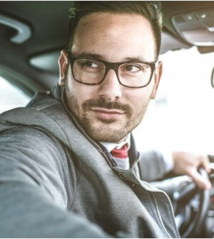 Man with glasses in car looking over his shoulder